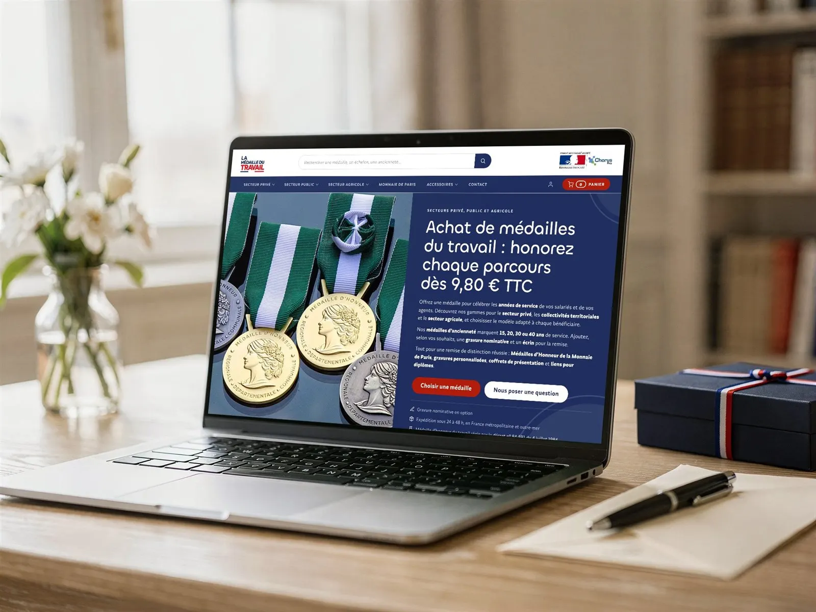 Boutique en ligne La Médaille du Travail, vente de médailles du travail, ouverte sur un ordinateur portable dans un bureau à côté d’un coffret tricolore